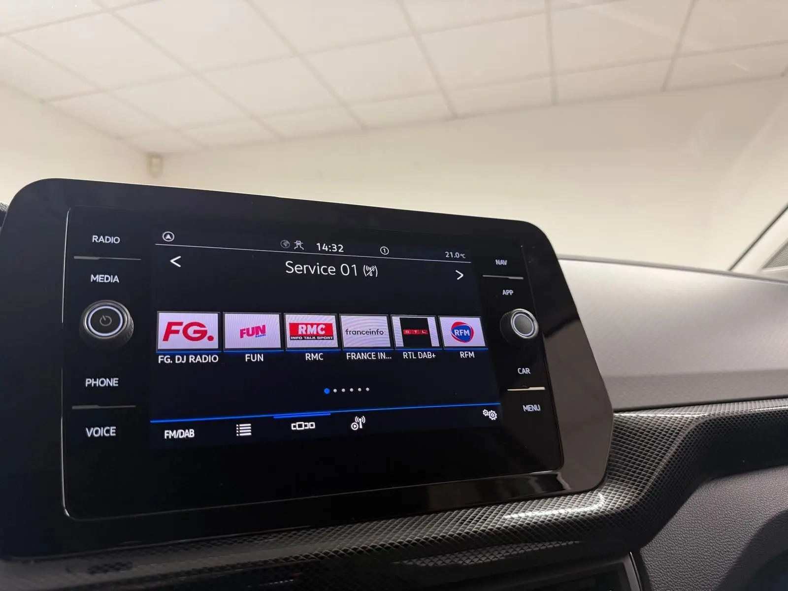 Vue intérieure du tableau de bord du Volkswagen T-Cross gris cendre 2025, écran tactile multimédia affichant les stations radio.