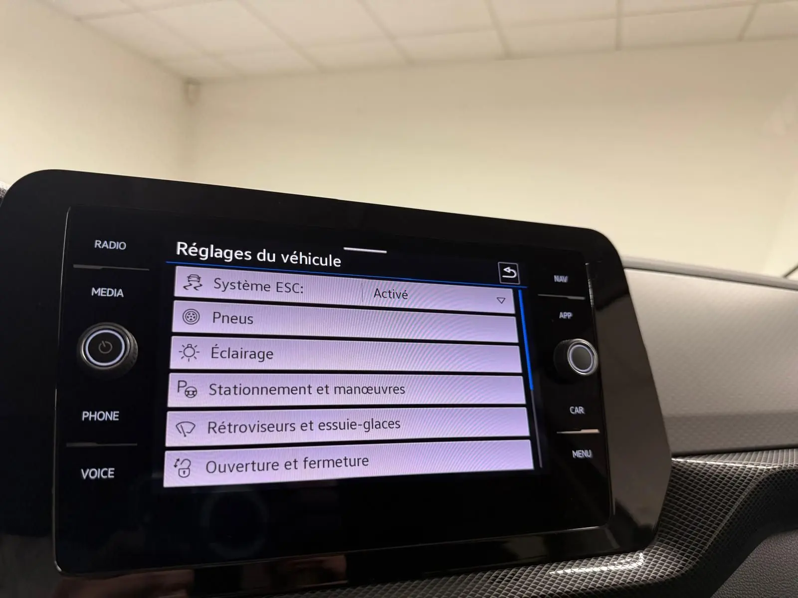 Écran tactile central du Volkswagen T-Cross 2025 affichant les réglages du véhicule dans un intérieur moderne gris.
