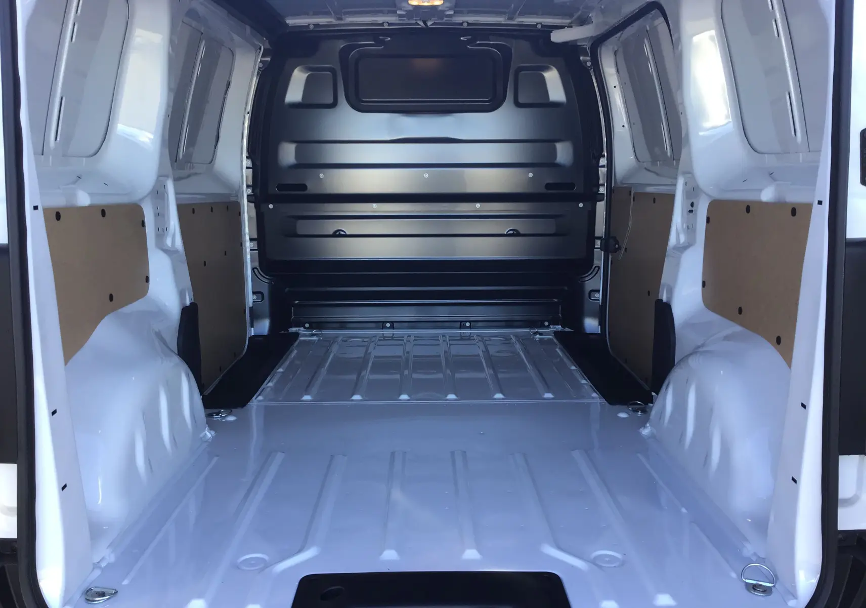 Vue intérieure arrière du fourgon blanc Peugeot Expert 2024, montrant l'espace de chargement vide et les parois latérales renforcées.