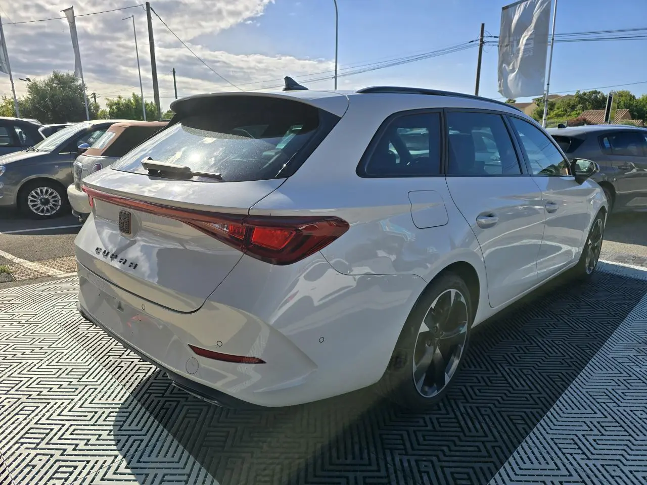 Vue 3/4 arrière droite d'une CUPRA Leon Sportstourer blanche Nevada avec feux arrière LED et jantes alliage 18 pouces.