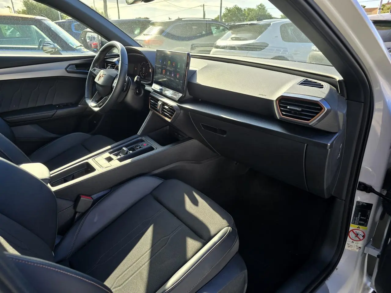 Intérieur de la CUPRA Leon Sportstourer blanc Nevada, vue côté conducteur avec tableau de bord digital et écran tactile central.