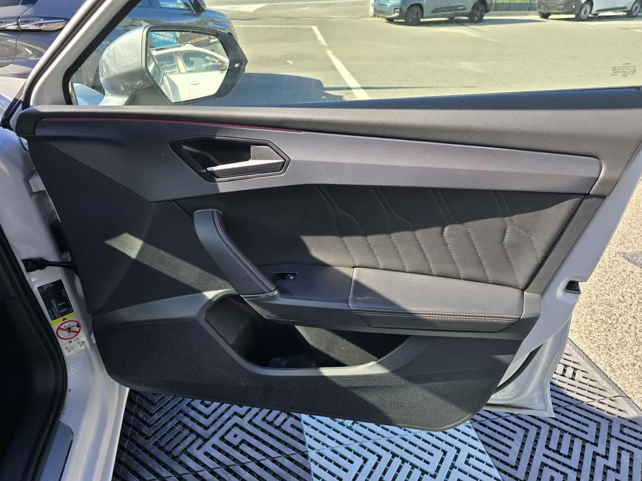 Intérieur de la porte avant gauche d'une CUPRA Leon Sportstourer blanc Nevada, avec garniture noire et surpiqûres contrastées.