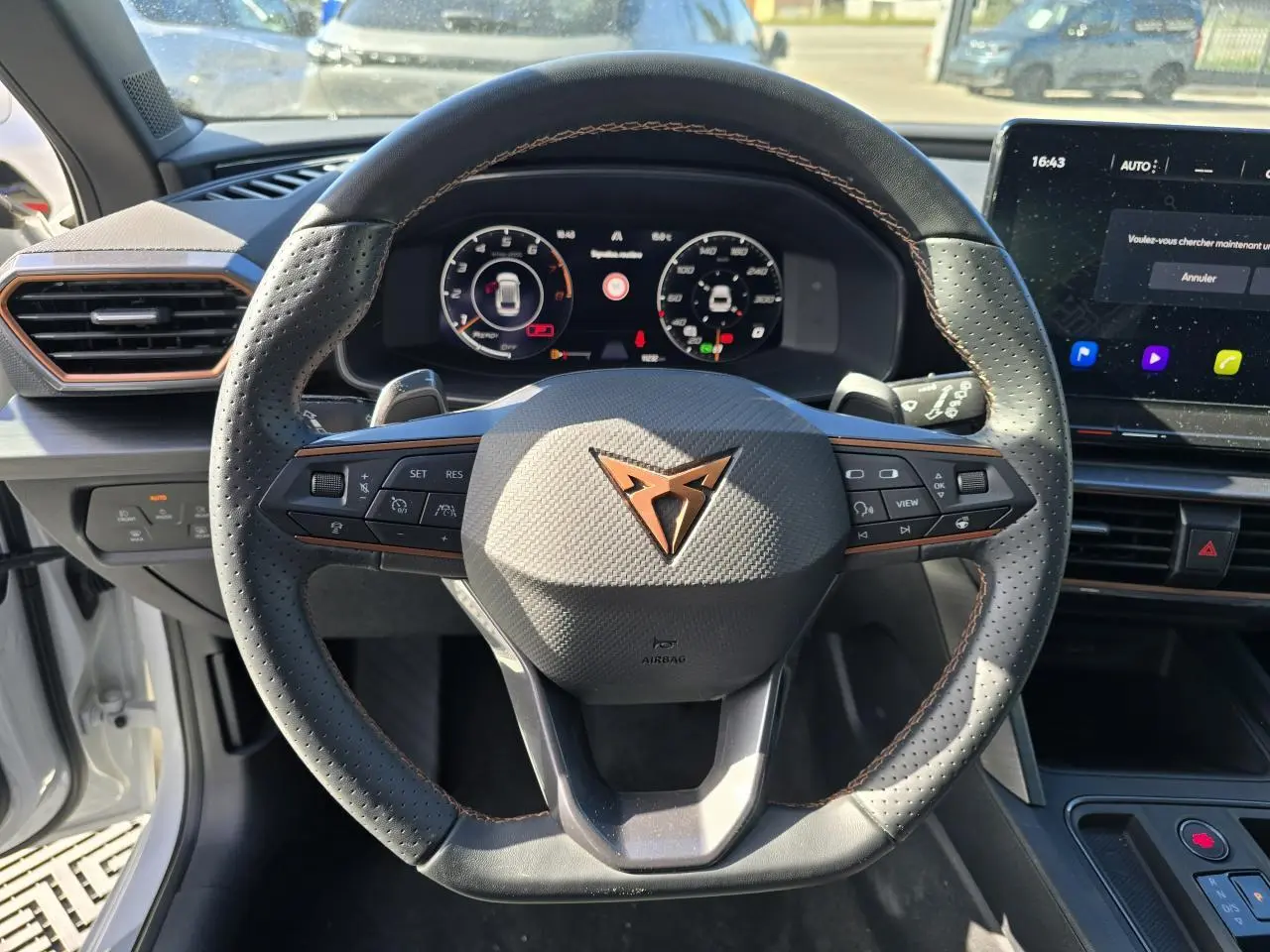 Volant Cupra perforé avec logo cuivre, tableau de bord digital et écran tactile dans l'habitacle d'une Leon Sportstourer blanche.