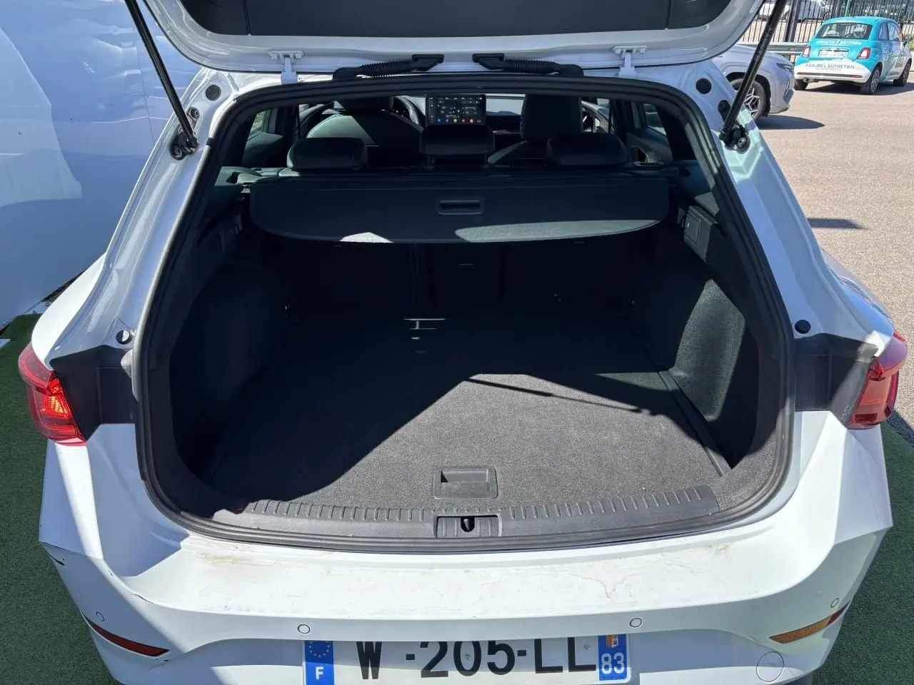 Vue arrière du coffre ouvert d'une CUPRA Leon Sportstourer blanc Nevada, avec feux arrière LED visibles.