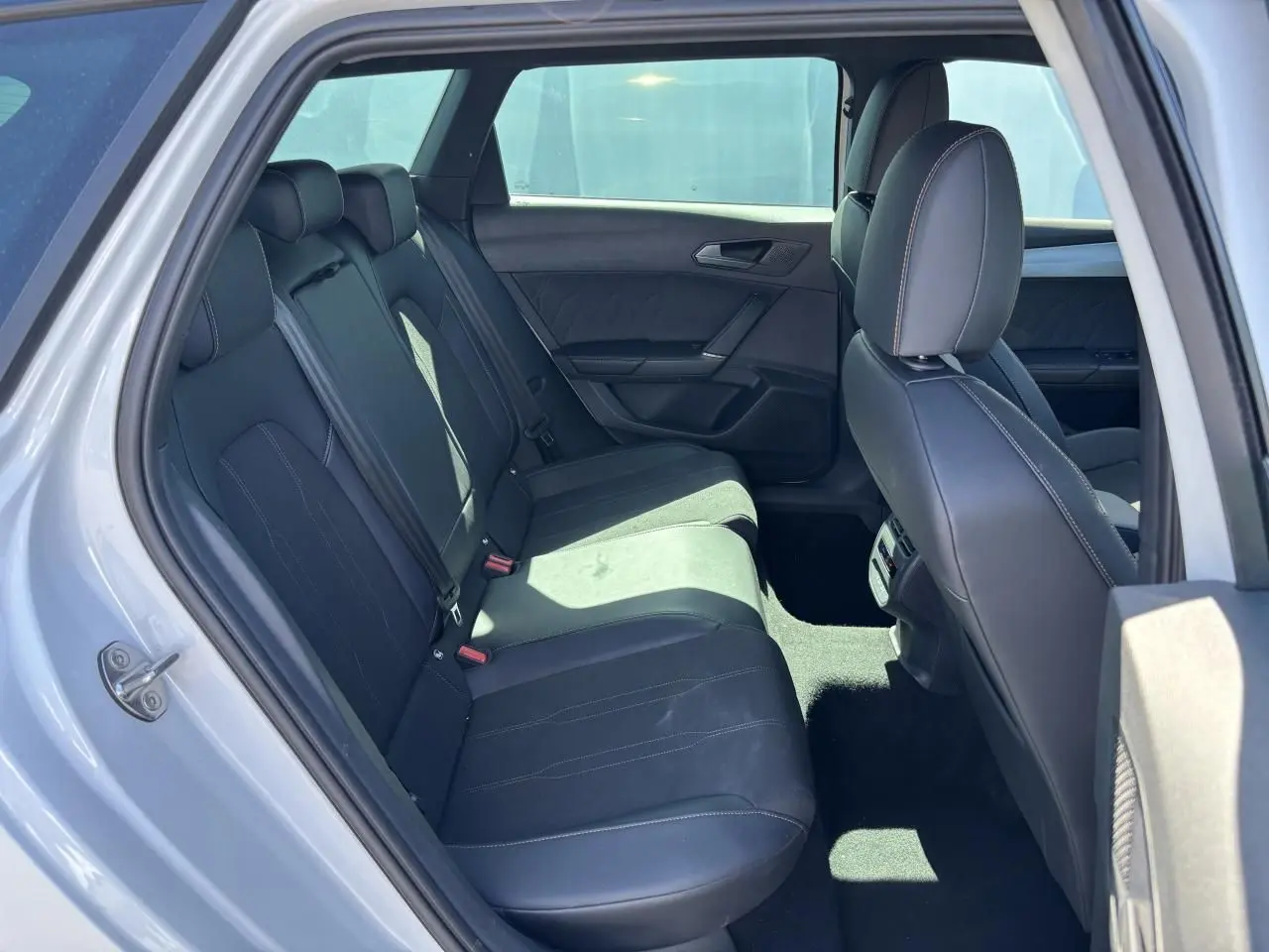 Vue intérieure arrière montrant les sièges noirs et les finitions du CUPRA Leon Sportstourer blanc Nevada 2024.