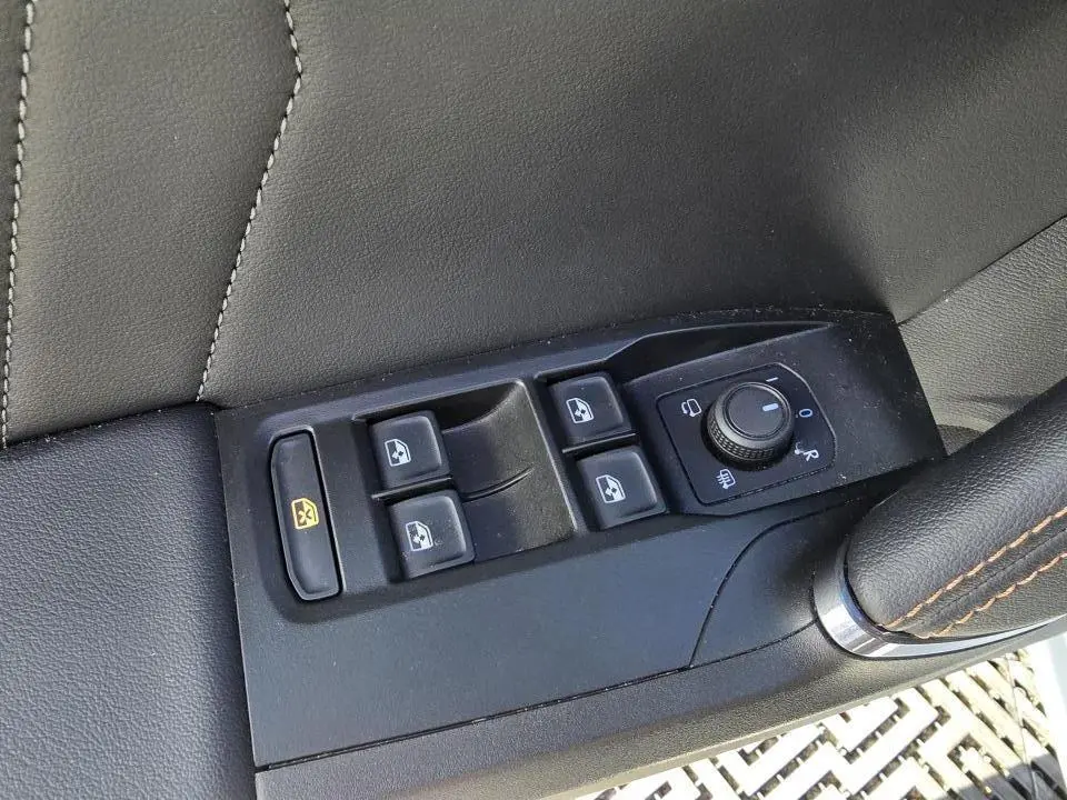 Gros plan sur les commandes des vitres et des rétroviseurs côté conducteur d'une CUPRA Leon Sportstourer 2024 en cuir noir.