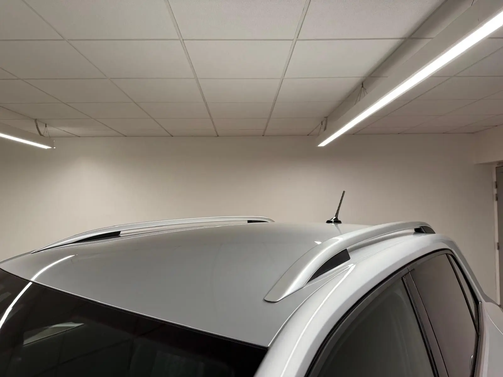 Vue en plongée du toit argent métallisé du Volkswagen T-Cross 1.5 TSI 150 DSG7 R-Line avec barres de toit et antenne.