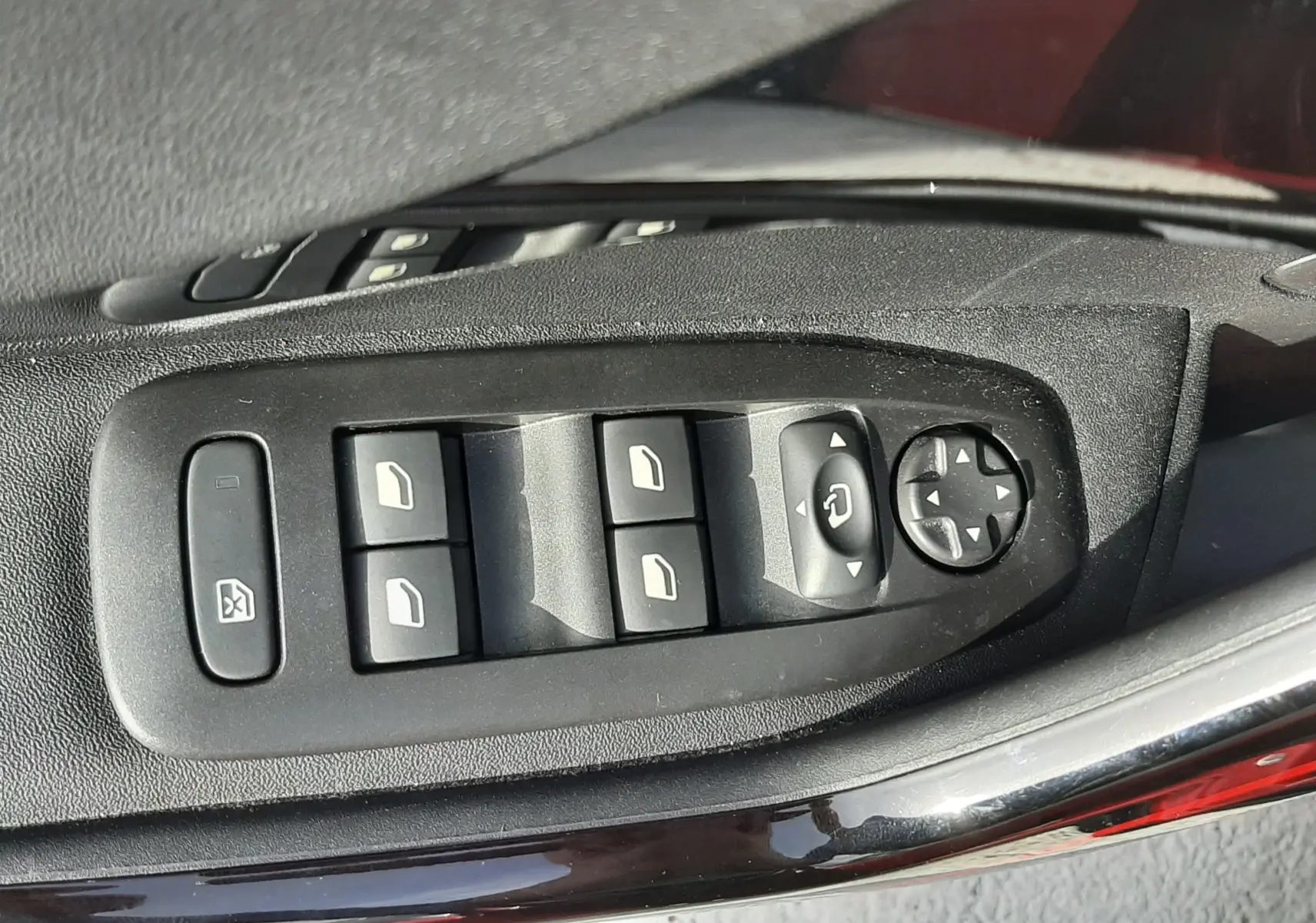 Gros plan sur les commandes des vitres et rétroviseurs côté conducteur d'une Peugeot 2008 rouge Ultimate Metal.