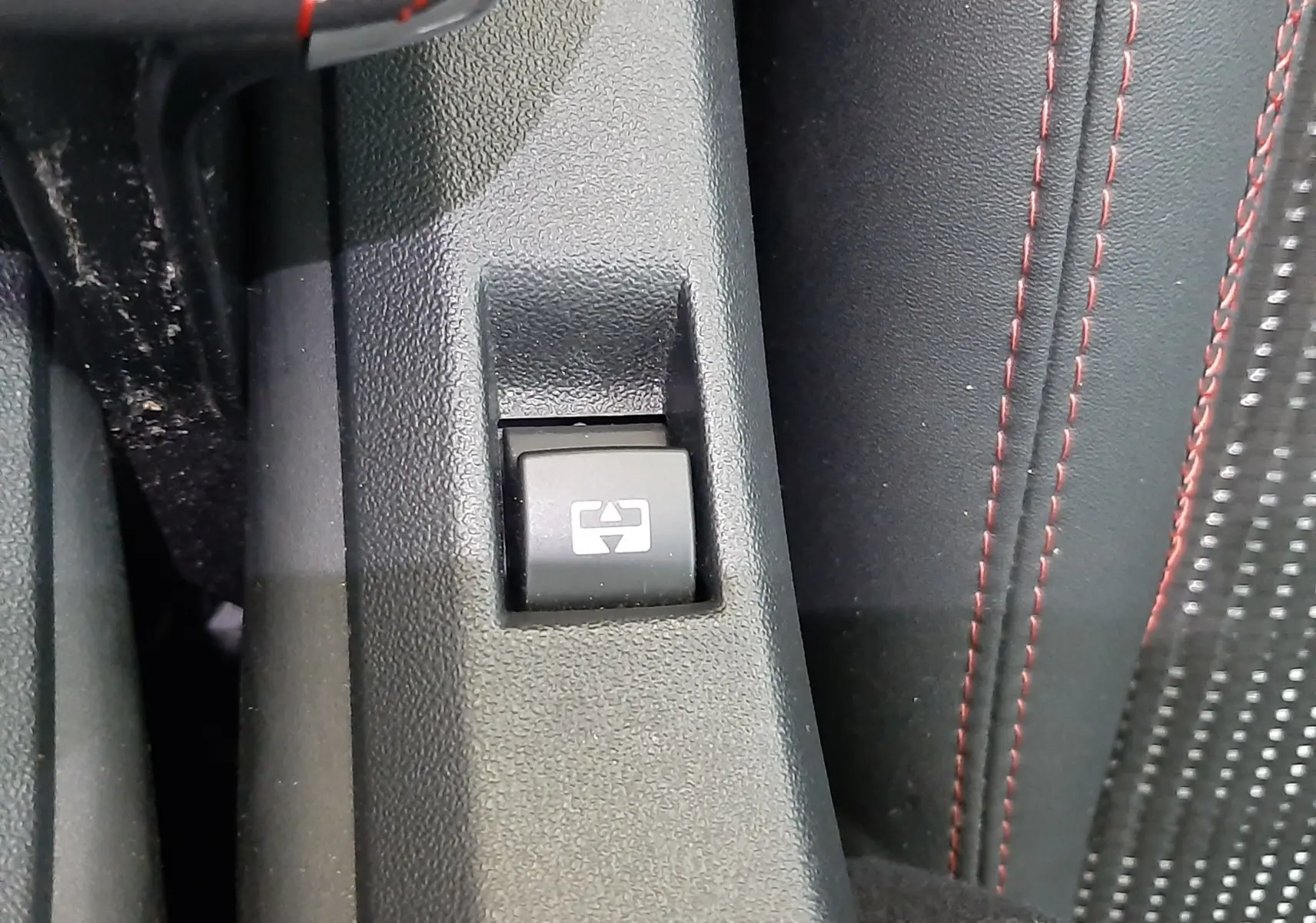 Gros plan sur le bouton de commande de vitre électrique avec surpiqûres rouges sur la console centrale du Peugeot 2008 GT Line.