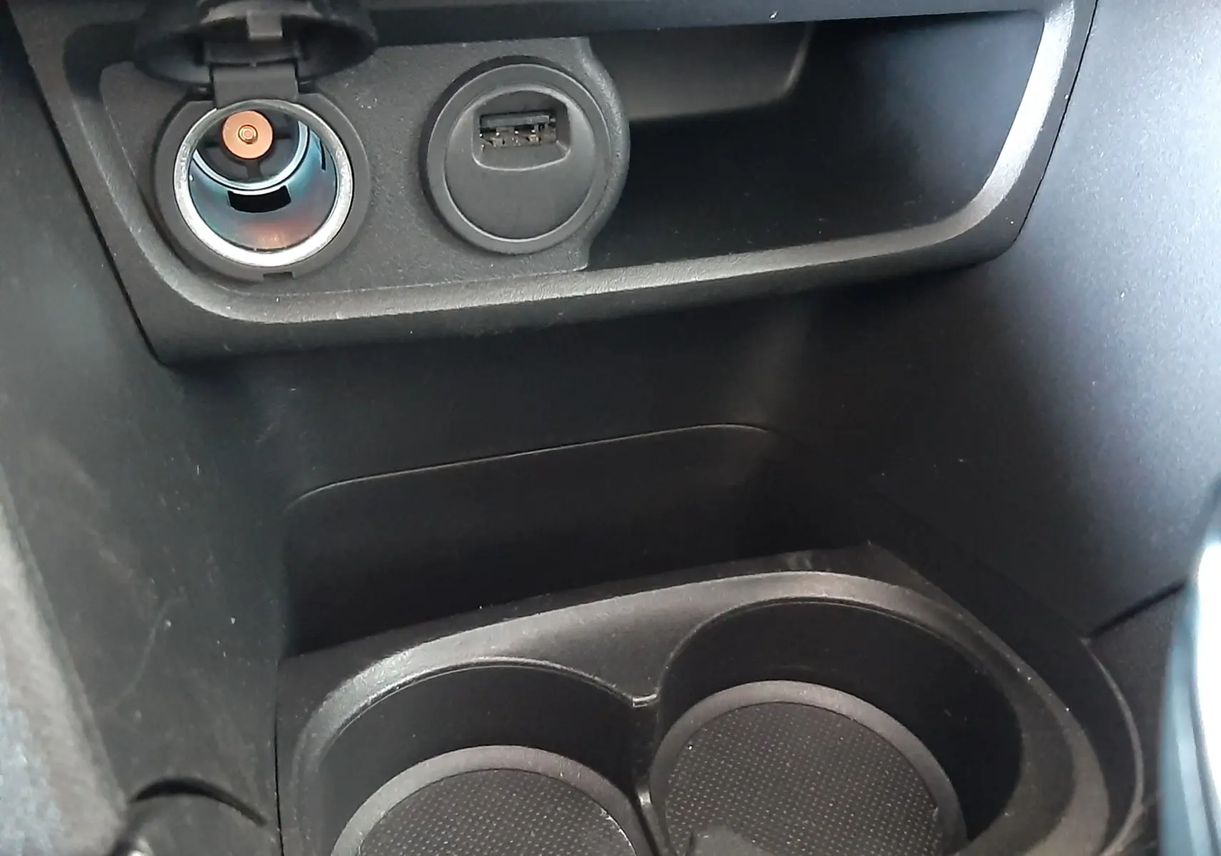 Prise allume-cigare et port USB au-dessus des porte-gobelets dans l'habitacle noir du Peugeot 2008 GT Line 2019.