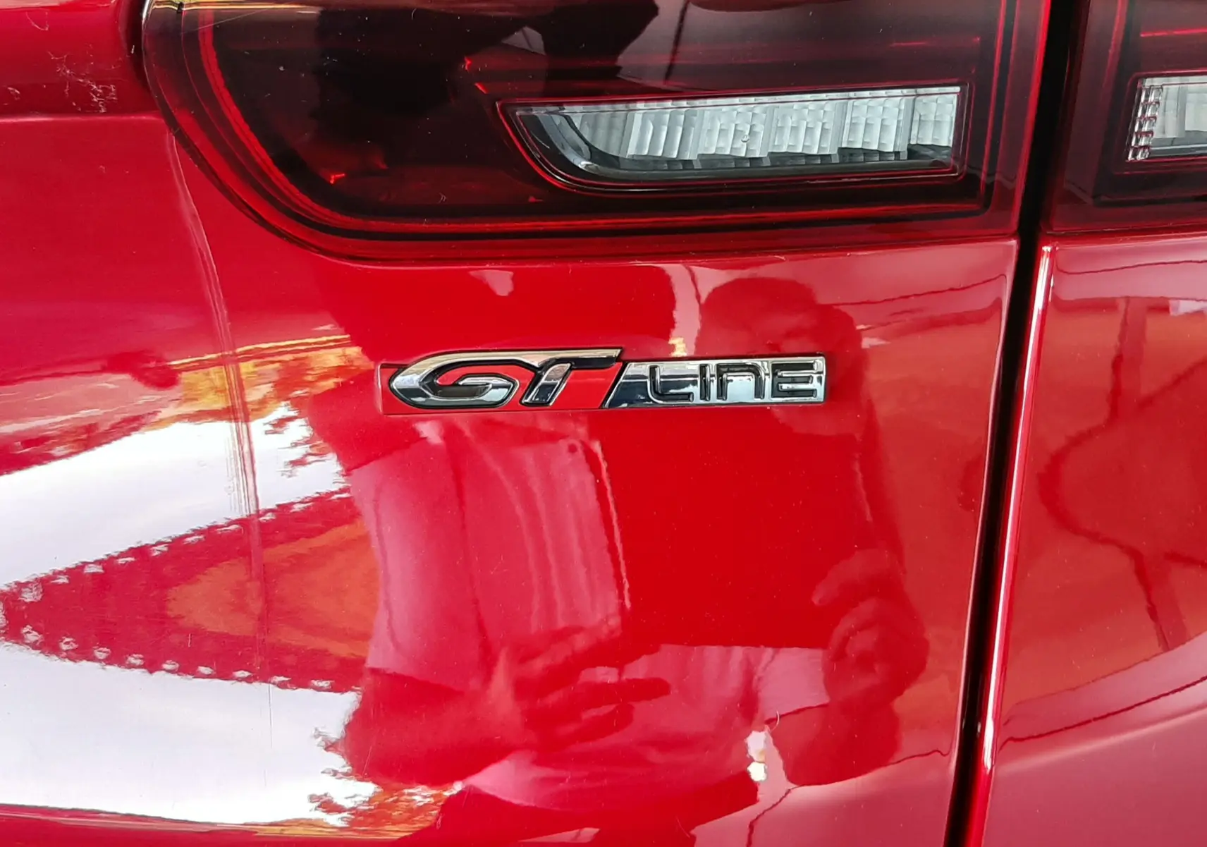 Gros plan sur le feu arrière et l'emblème GT Line du Peugeot 2008 rouge Ultimate Metal côté arrière droit.