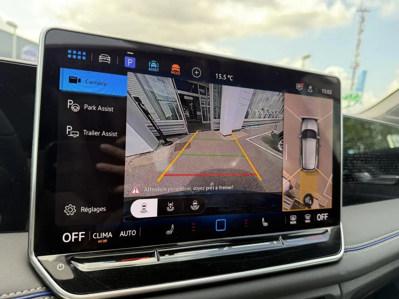 Écran tactile intérieur du Volkswagen Tiguan 2024 affichant l'assistance au stationnement avec vue caméra et plan 360° du véhicule.