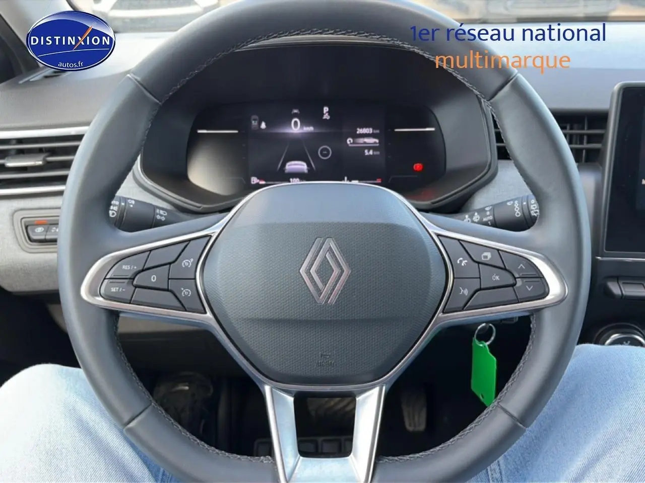 Vue rapprochée du volant multifonction noir de la Renault Clio V avec tableau de bord numérique en arrière-plan.