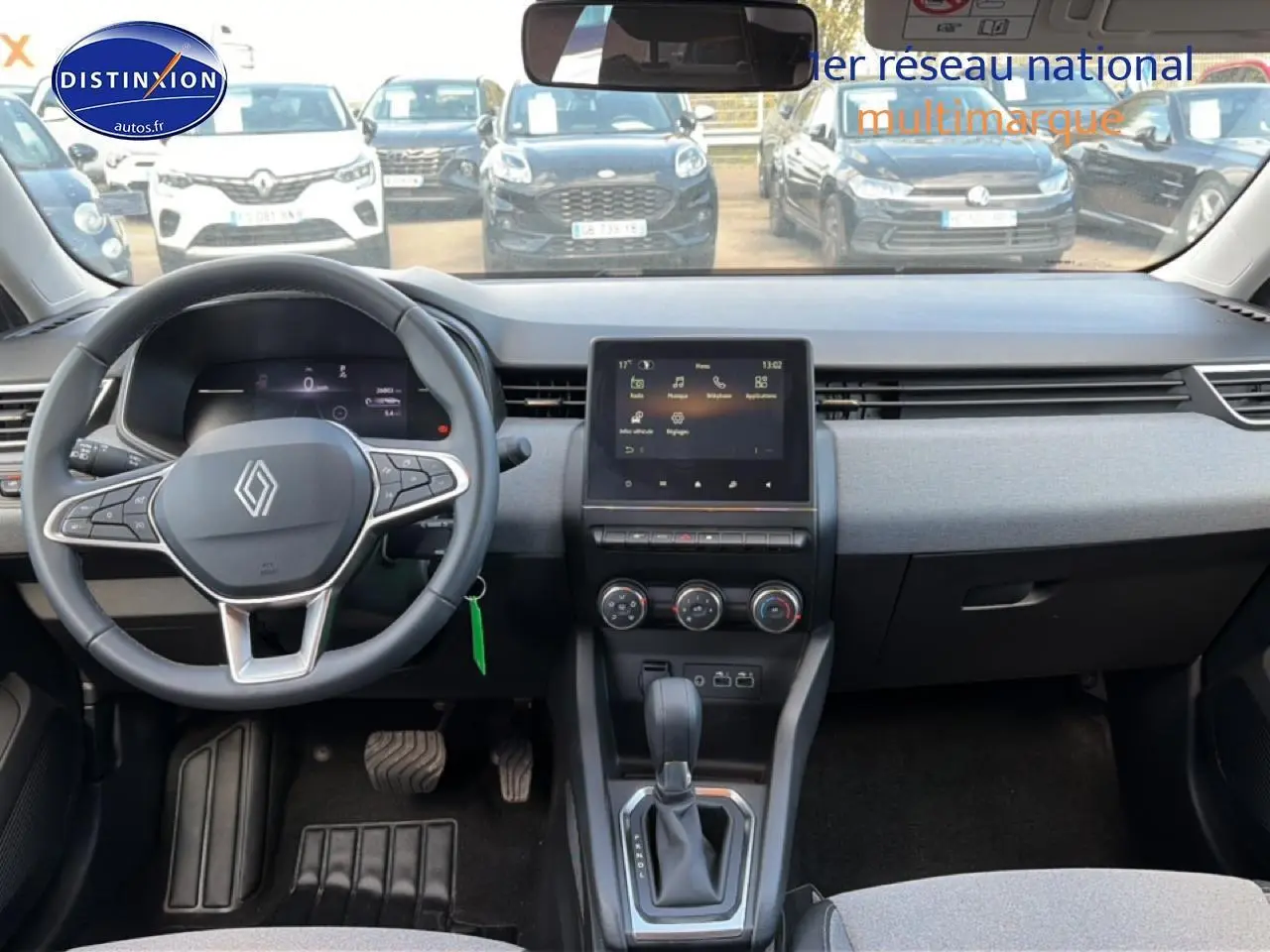 Vue intérieure avant de la Renault Clio V gris foncé, montrant le volant multifonction et l’écran tactile central.