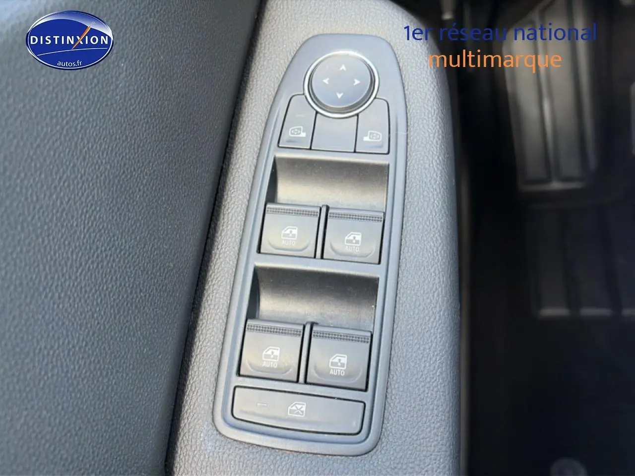 Gros plan sur les commandes de lève-vitres électriques côté conducteur de la Renault Clio V gris foncé, intérieur tissu noir.