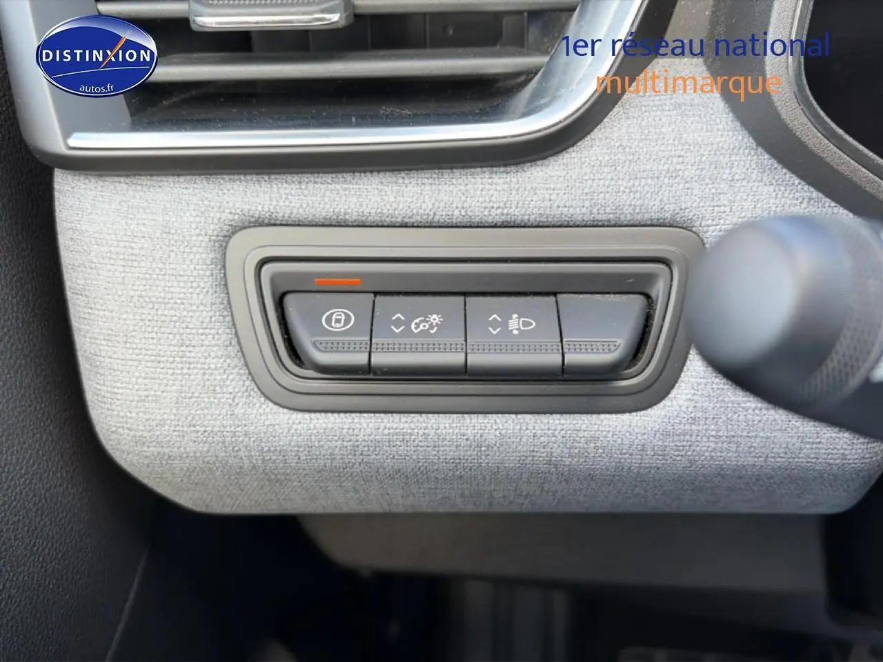 Gros plan sur les commandes d’éclairage et verrouillage sur tableau de bord gris clair de Renault Clio V 2025.