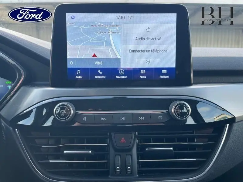 Vue rapprochée de l’écran tactile central et des commandes audio du tableau de bord du Ford Kuga 2023 bleu azur.