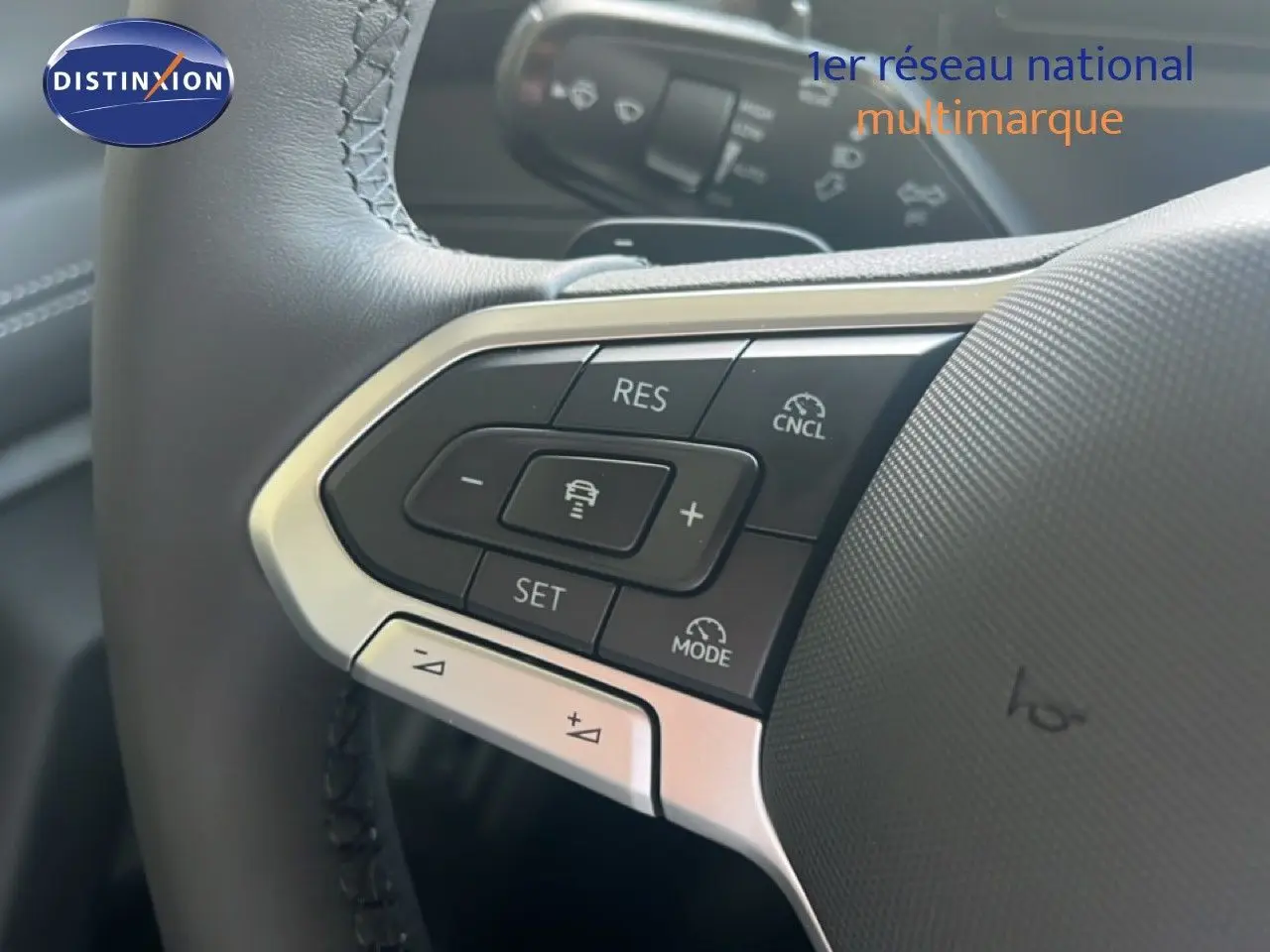 Gros plan sur les commandes au volant du Volkswagen Tiguan 2026, cuir noir avec boutons multifonctions et régulateur adaptatif.