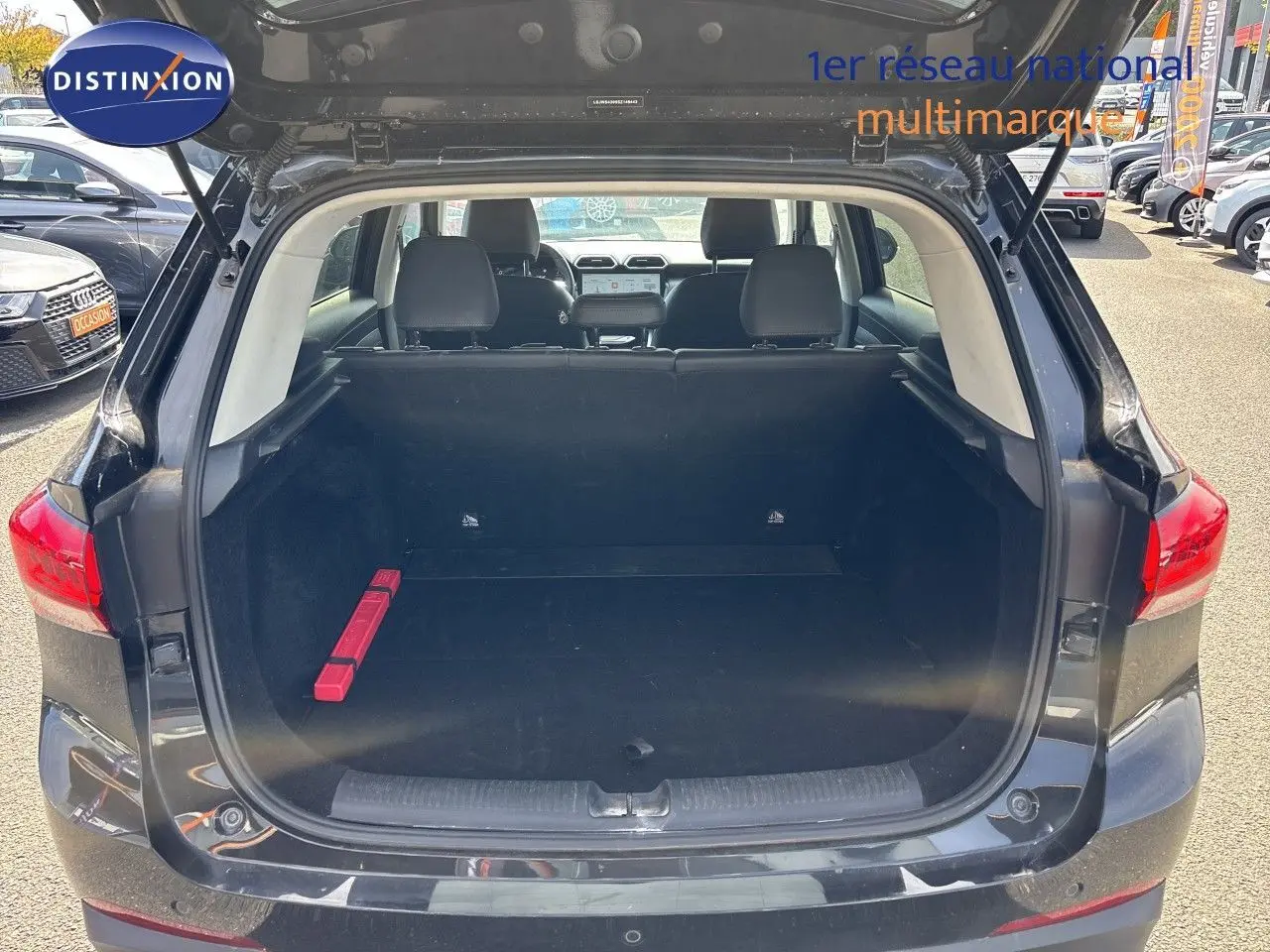 Vue arrière du coffre ouvert du MG ZS 1.5L Hybrid+ 197ch Luxury en Pebble Black Metal, intérieur spacieux et noir.