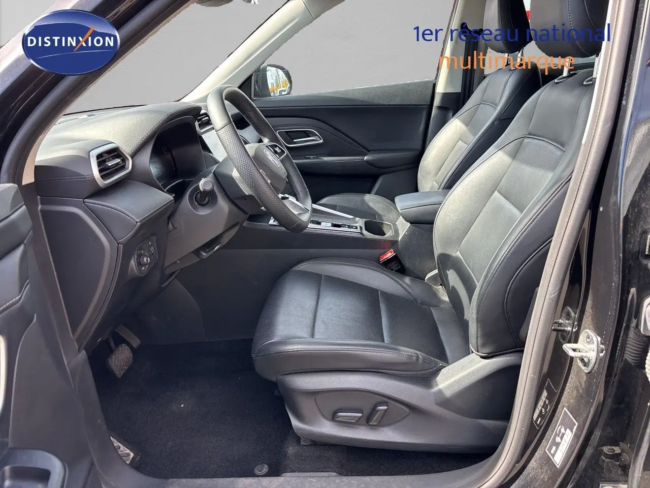 Vue intérieure côté conducteur du MG MOTOR ZS 1.5L HYBRID+ 197CH LUXURY 2025 en Pebble Black, sièges cuir noirs et volant multifonction.