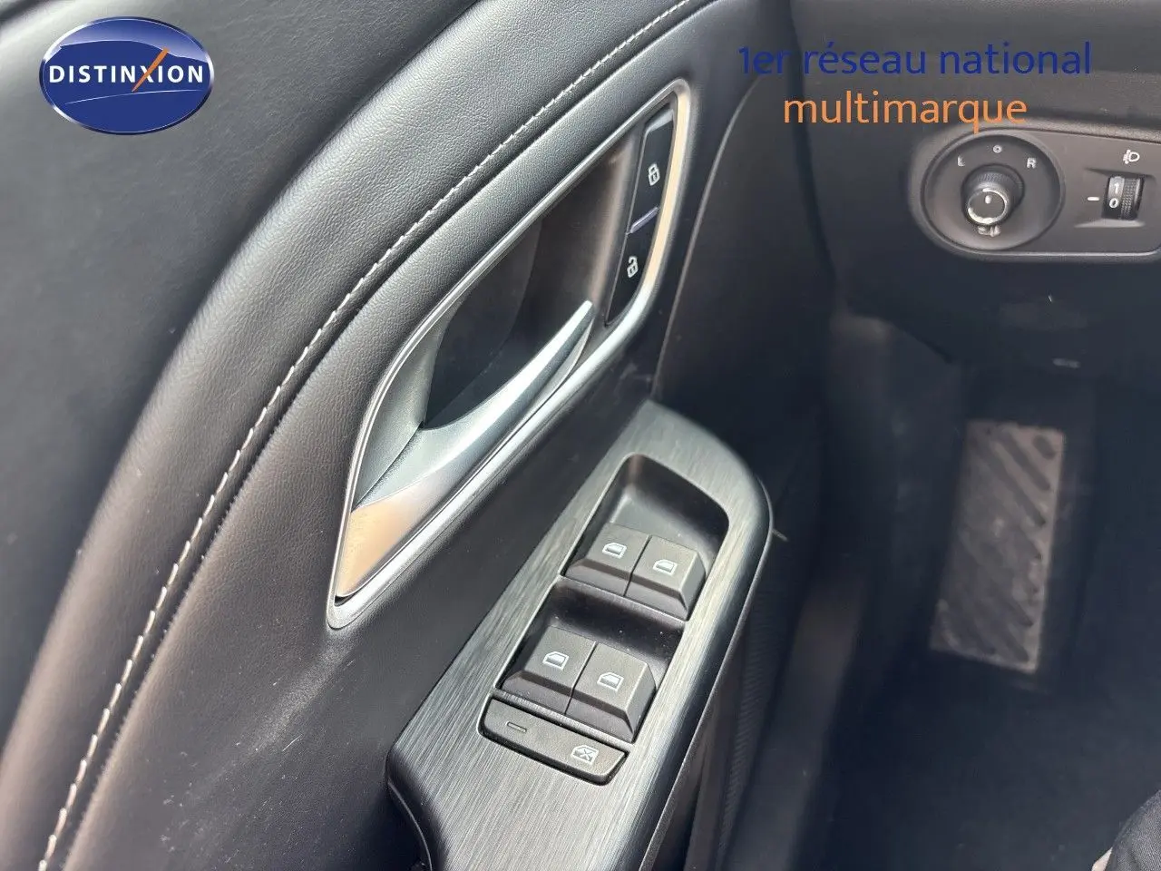 Gros plan sur la porte côté conducteur du MG ZS 2025 en Pebble Black, avec commandes de vitres et poignée argentée.