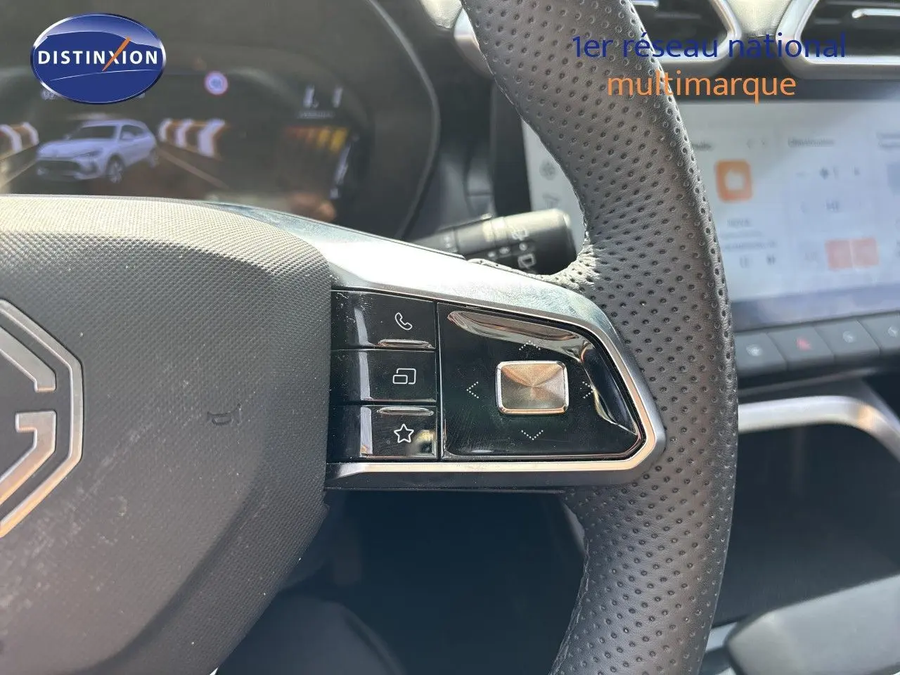Gros plan sur la partie droite du volant perforé noir du MG ZS 1.5L Hybrid+ 2025 avec commandes intégrées et écran tactile en arrière-plan.