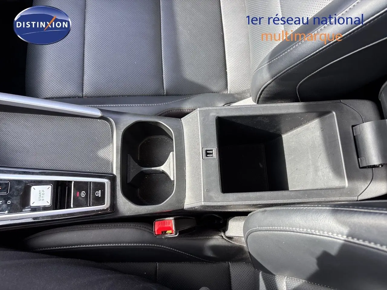 Vue plongeante sur la console centrale noire en cuir perforé du MG ZS 1.5L Hybrid+ 197ch Luxury avec porte-gobelets et rangement ouvert.