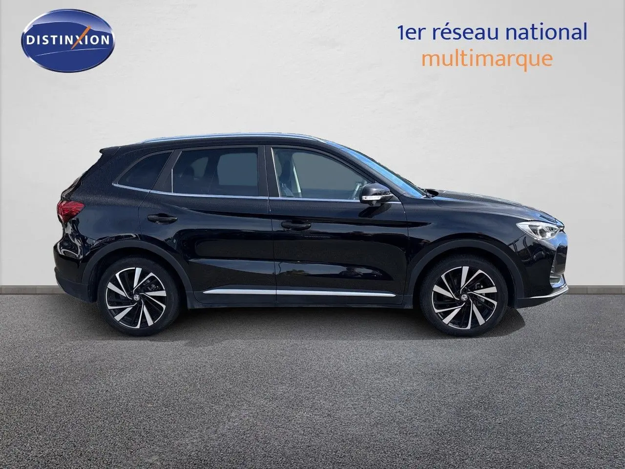 Vue de profil côté gauche du MG MOTOR ZS 1.5L HYBRID+ 197CH LUXURY en noir Pebble Black Metal avec jantes bi-ton.