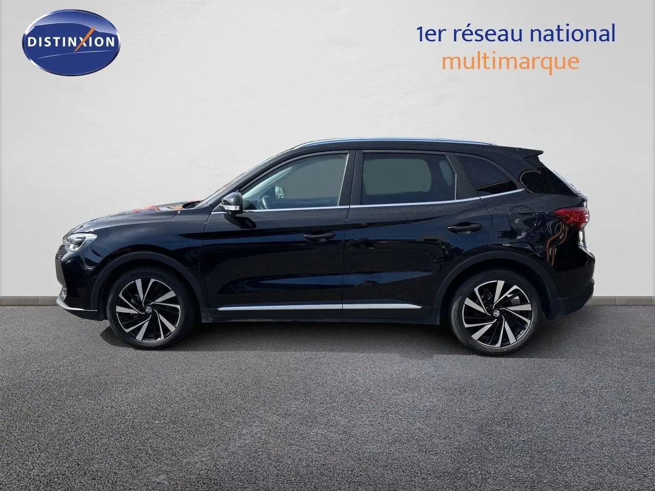 Vue de profil côté gauche d’un MG ZS 1.5L Hybrid+ 197ch Luxury en noir Pebble Black Metal avec jantes alliage bicolores.