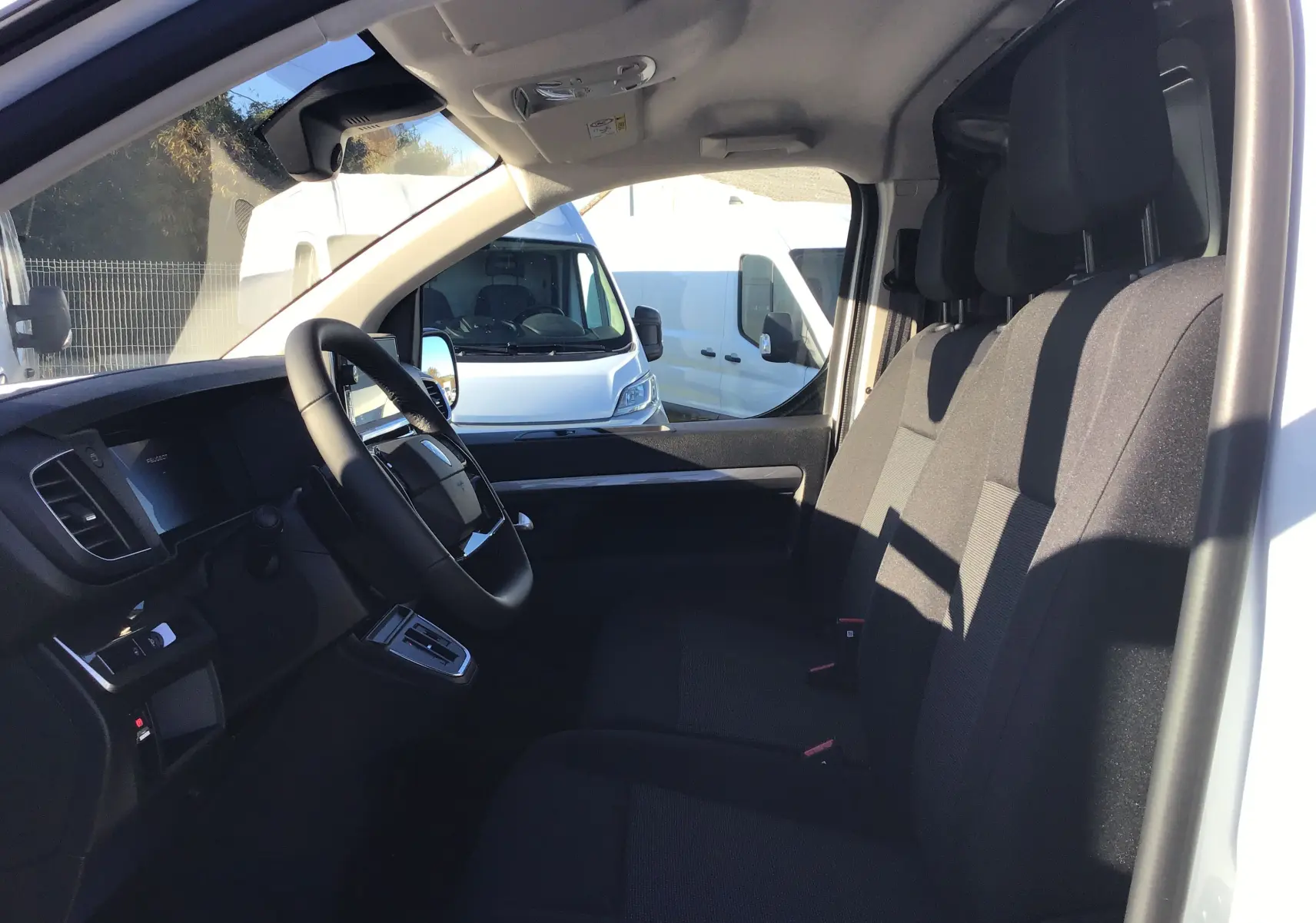 Intérieur du Peugeot Expert Fourgon blanc 2024 vu côté conducteur, montrant les sièges avant et le tableau de bord.