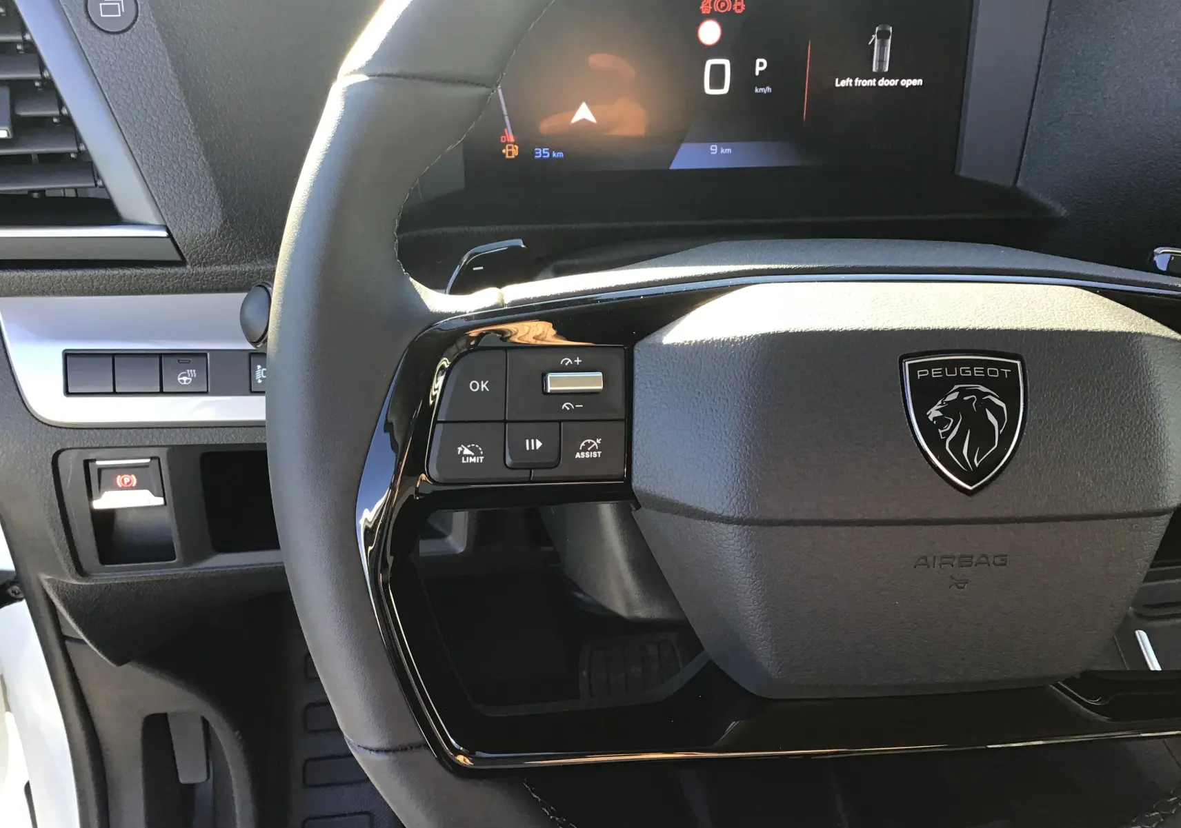 Vue rapprochée du volant cuir noir du Peugeot Expert Fourgon 2024 avec commandes intégrées et tableau de bord numérique.