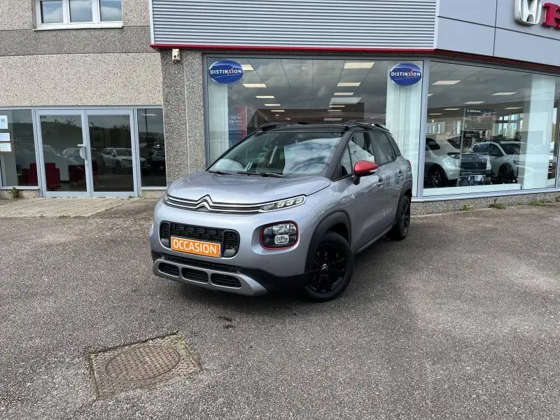 Citroën C3 Aircross gris acier vue 3/4 avant droit avec toit noir et rétroviseurs rouges devant concessionnaire