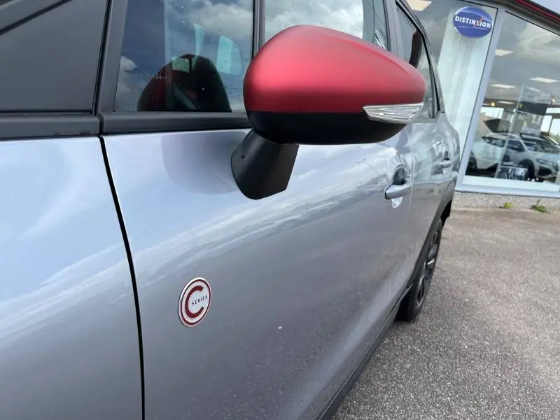 Gros plan sur le côté gauche d'une Citroën C3 Aircross gris acier avec rétroviseur rouge et badge C-Series.