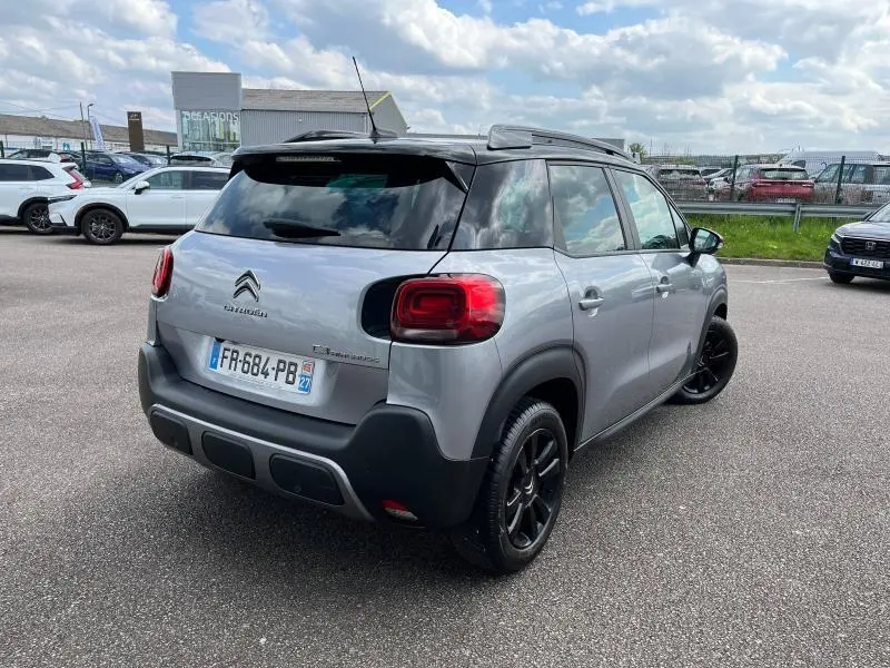 Citroën C3 Aircross gris acier vue 3/4 arrière droit avec toit noir et jantes noires en parking.