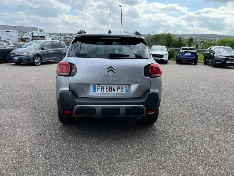 Vue arrière d'un Citroën C3 Aircross gris acier avec pare-chocs noir et feux arrière caractéristiques, stationné en extérieur.