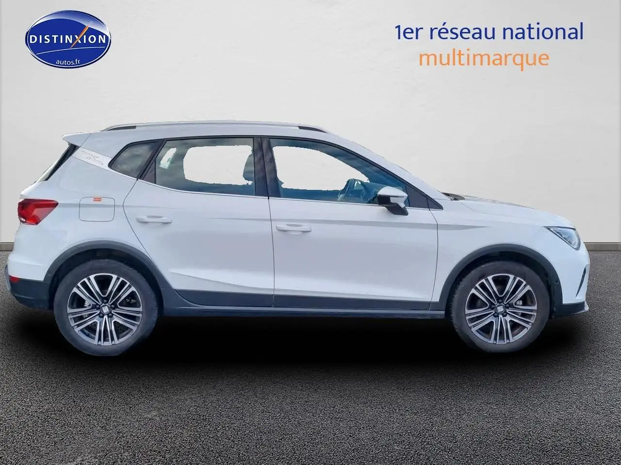 Profil droit d'un SUV blanc SEAT Arona 1.0 TSI 110 Xperience 2023 avec jantes alu 17 pouces et barres de toit.