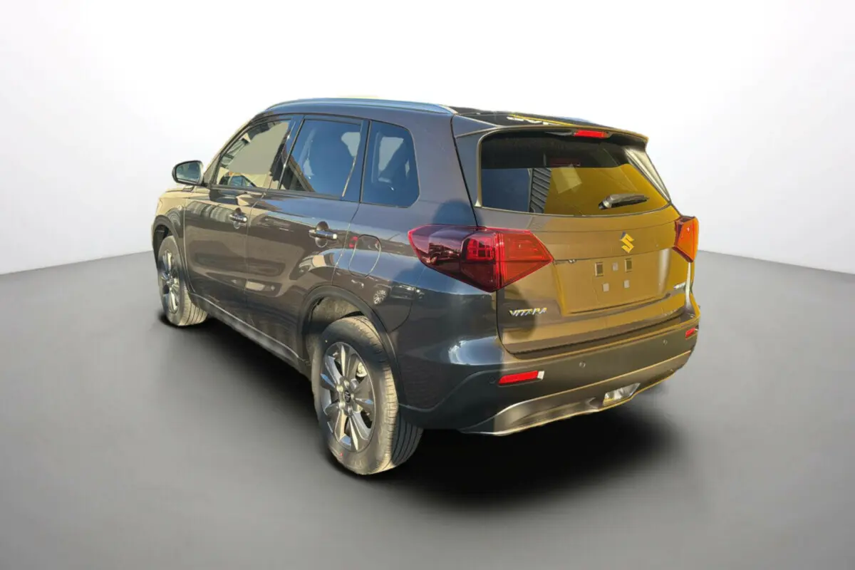 Suzuki Vitara 2025 gris titan en 3/4 arrière droit, avec feux arrière rouges et jantes alliage visibles.