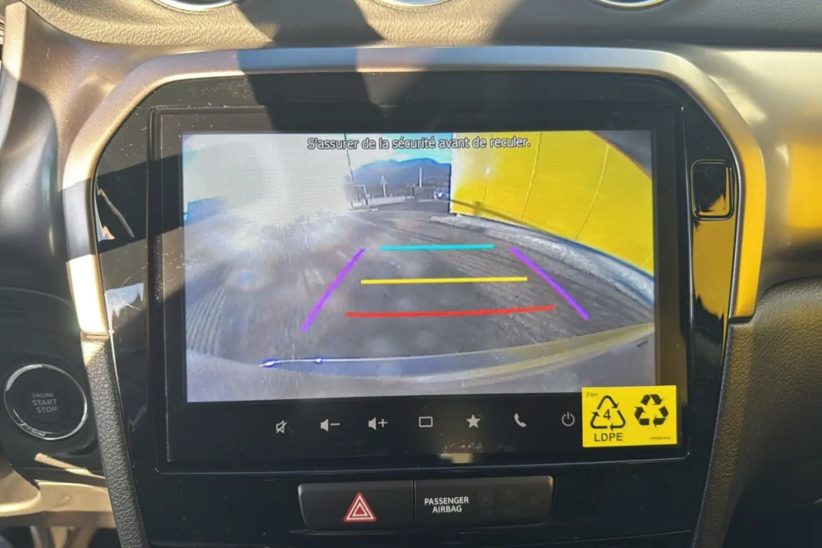 Écran central du Suzuki Vitara 2025 montrant la caméra de recul avec repères colorés dans un intérieur noir et gris.