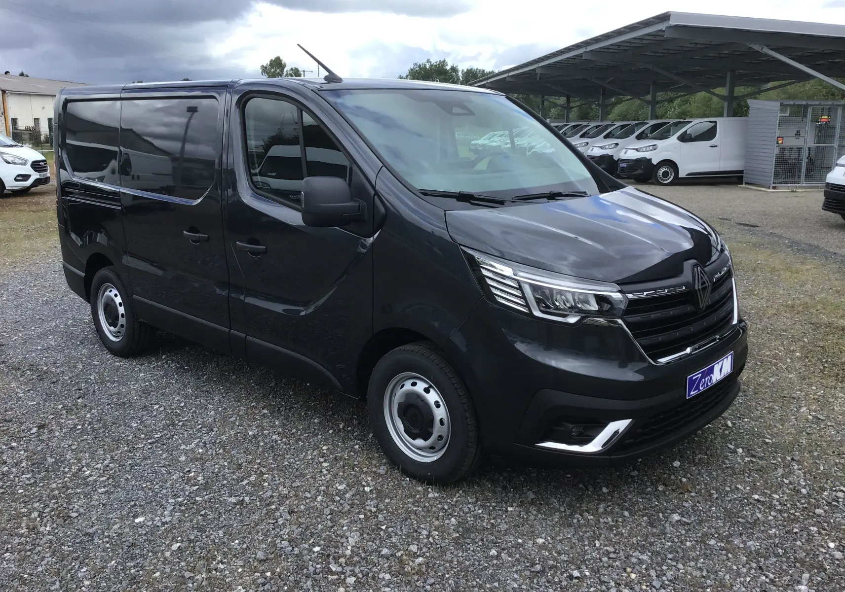 Renault Trafic Fourgon gris comète vu en 3/4 avant droit, avec calandre noire et phares LED distinctifs.