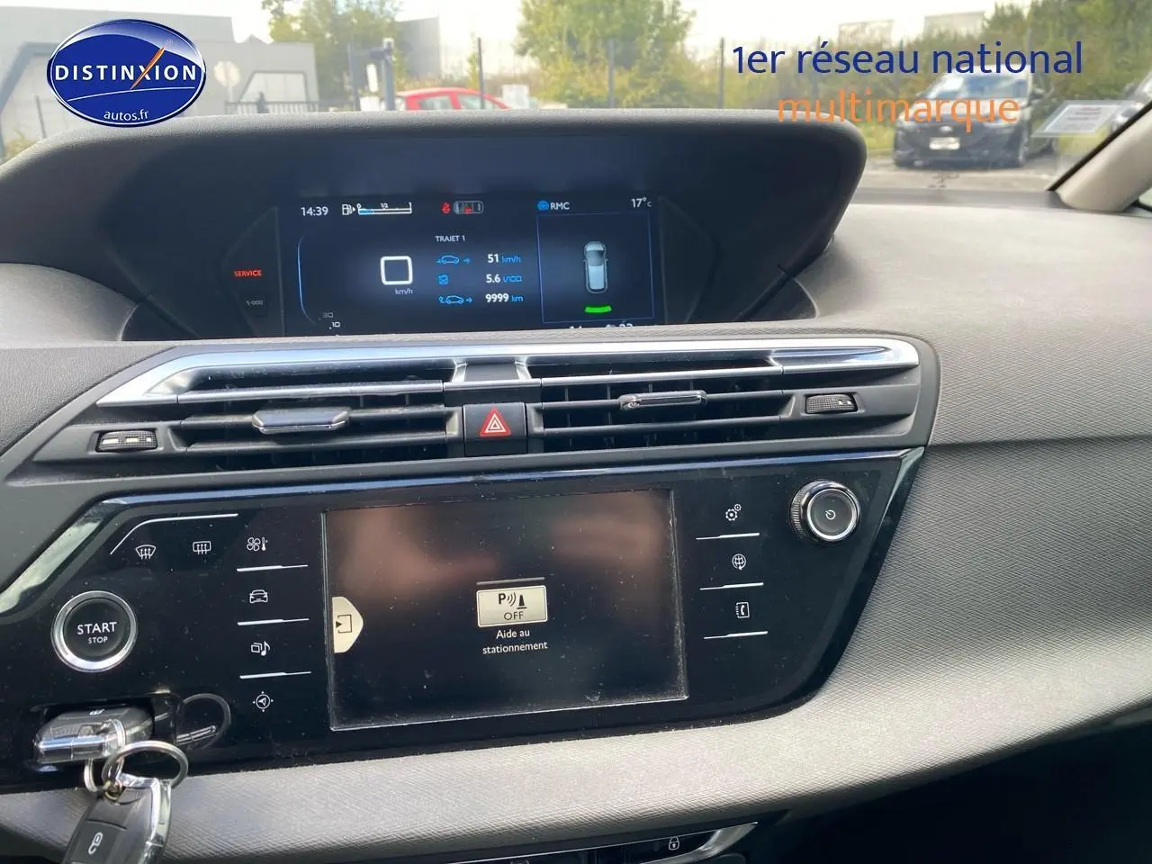 Tableau de bord et écran tactile central du Citroën C4 Picasso gris, avec affichage de l'aide au stationnement.