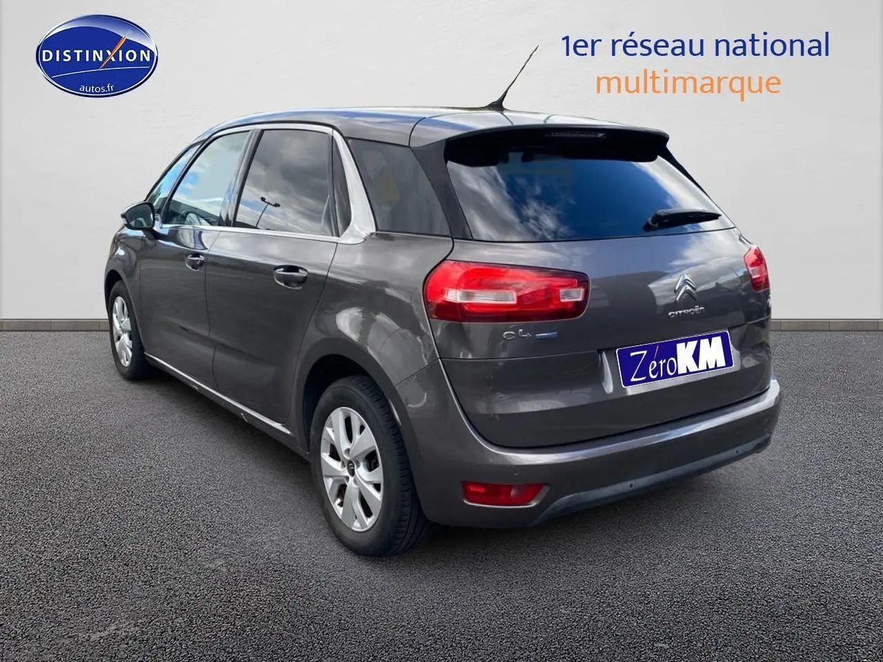 Vue 3/4 arrière droite d'une Citroën C4 Picasso gris métallisé avec vitres teintées et jantes alu.