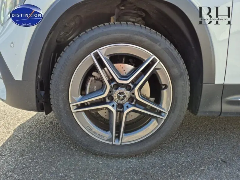 Gros plan sur la jante avant droite en alliage AMG du Mercedes GLB blanc polaire 2023, avec logo étoile visible au centre.