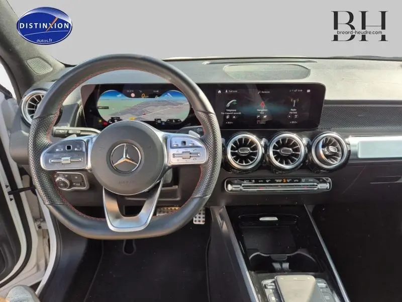 Vue intérieure du tableau de bord et volant sport Mercedes GLB 200 d AMG Line avec écran tactile et aérateurs ronds chromés.