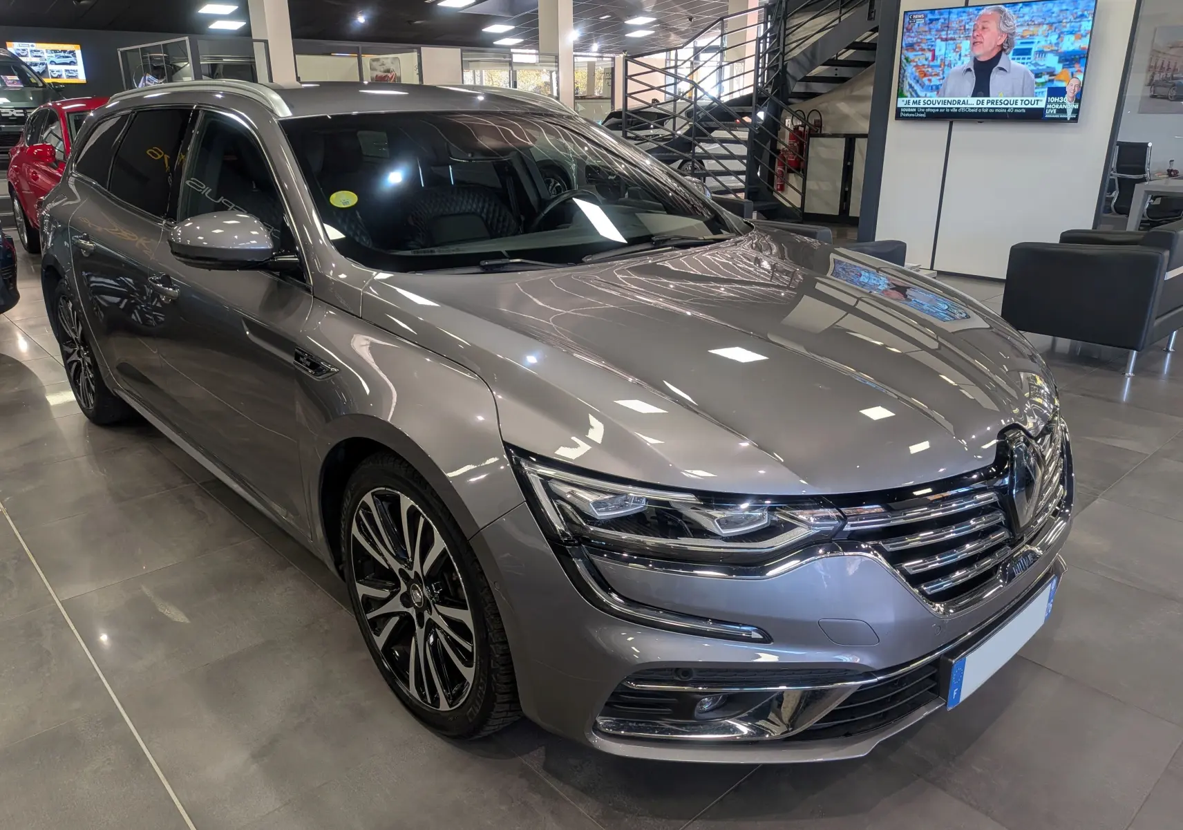Renault Talisman Estate gris Cassiopé vue 3/4 avant droit en intérieur avec jantes bi-ton et phares LED.