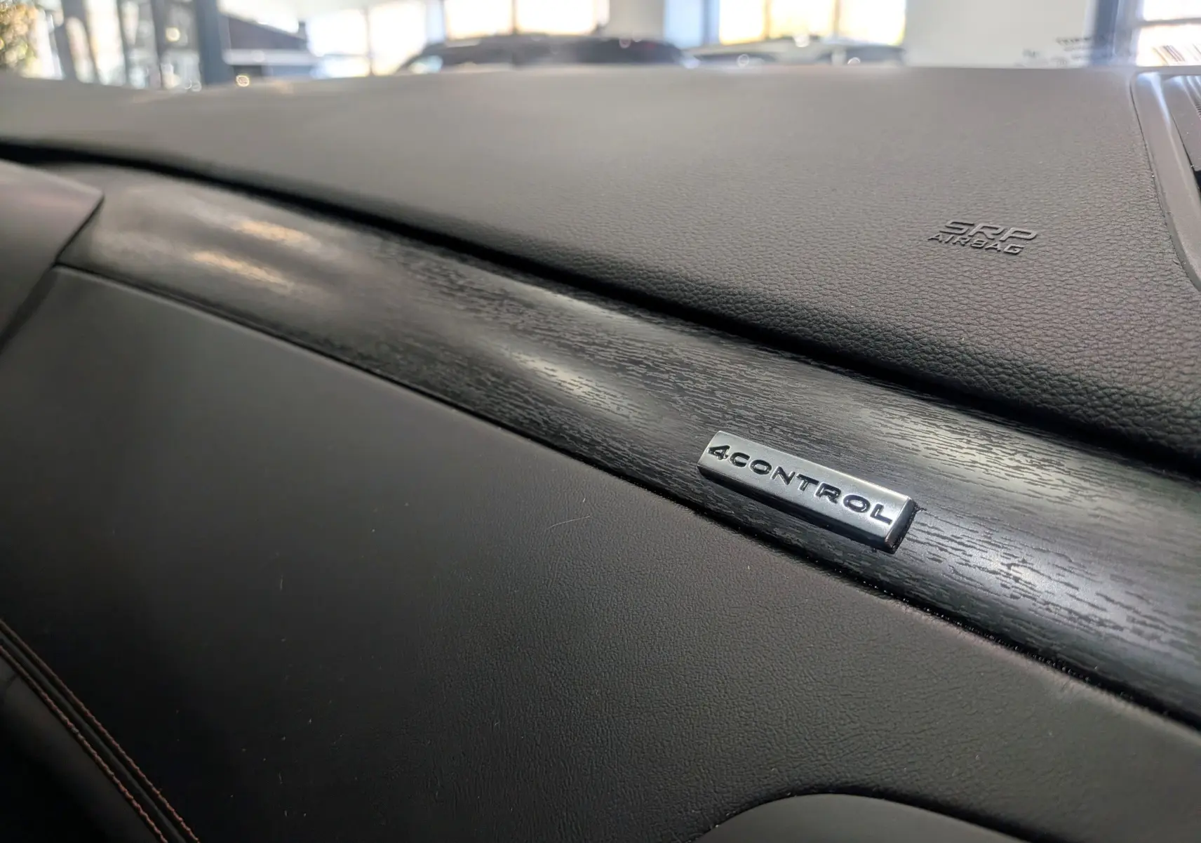 Gros plan sur la planche de bord noire avec insert bois et logo 4CONTROL dans une Renault Talisman Estate 2022.