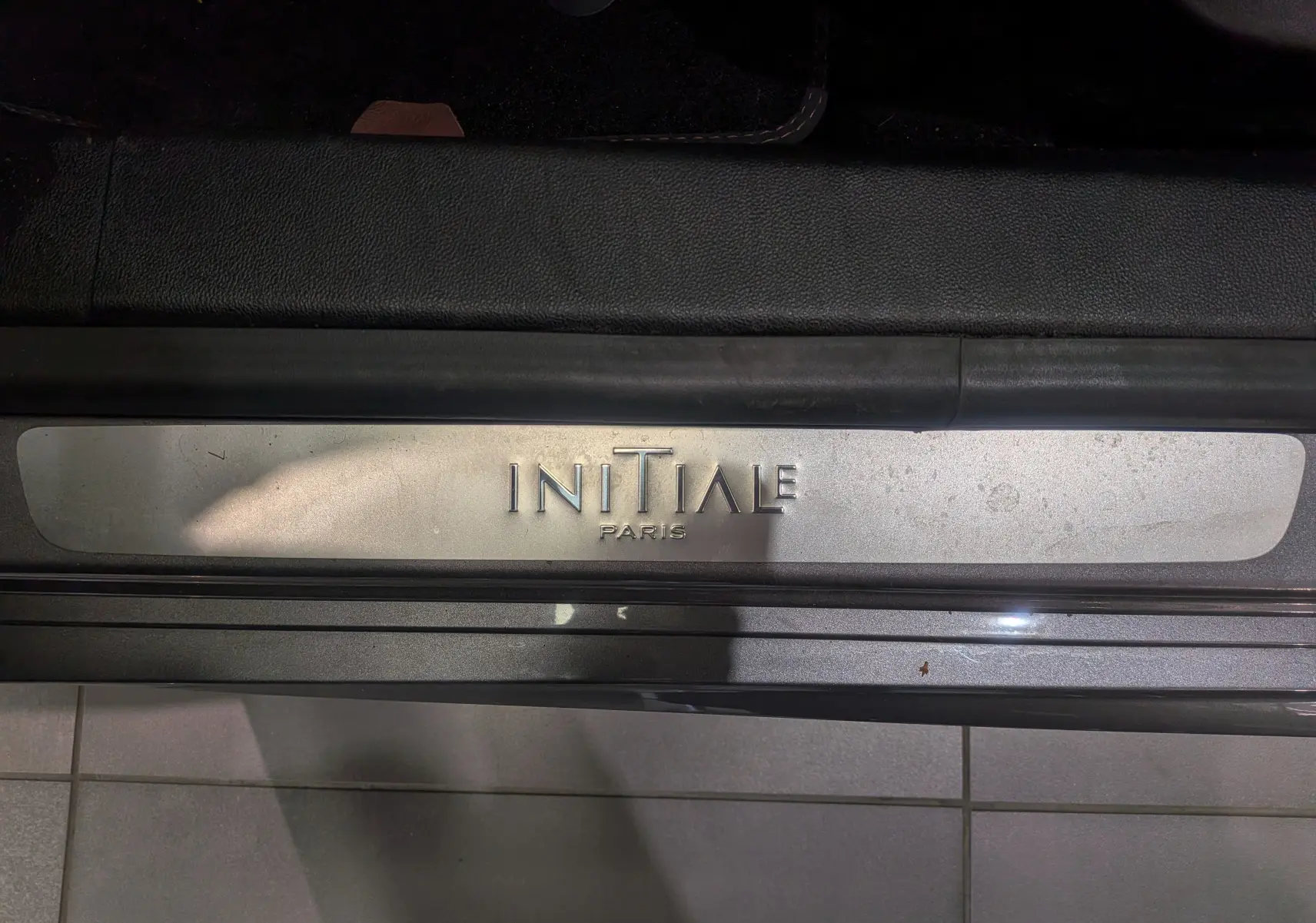 Gros plan sur la plaque de seuil de porte "Initiale Paris" du Renault Talisman Estate gris Cassiopé, version haut de gamme.