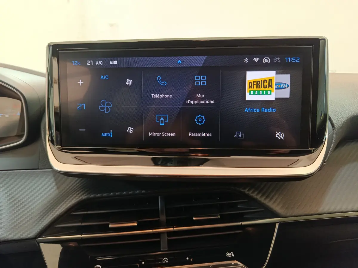 Écran tactile central affichant la climatisation et la radio dans l’habitacle gris du Peugeot 208 PureTech 100 S&S Allure.