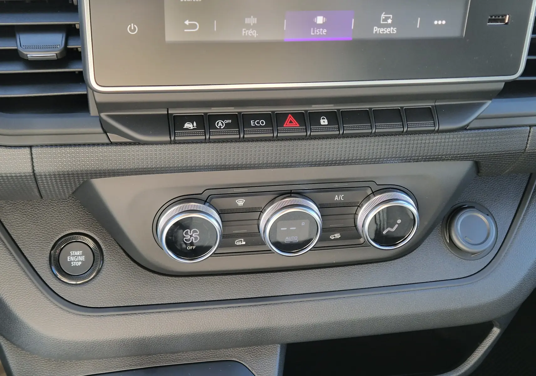 Vue rapprochée du tableau de bord du Renault Trafic Fourgon 2025, montrant les commandes de climatisation et le bouton start/stop.