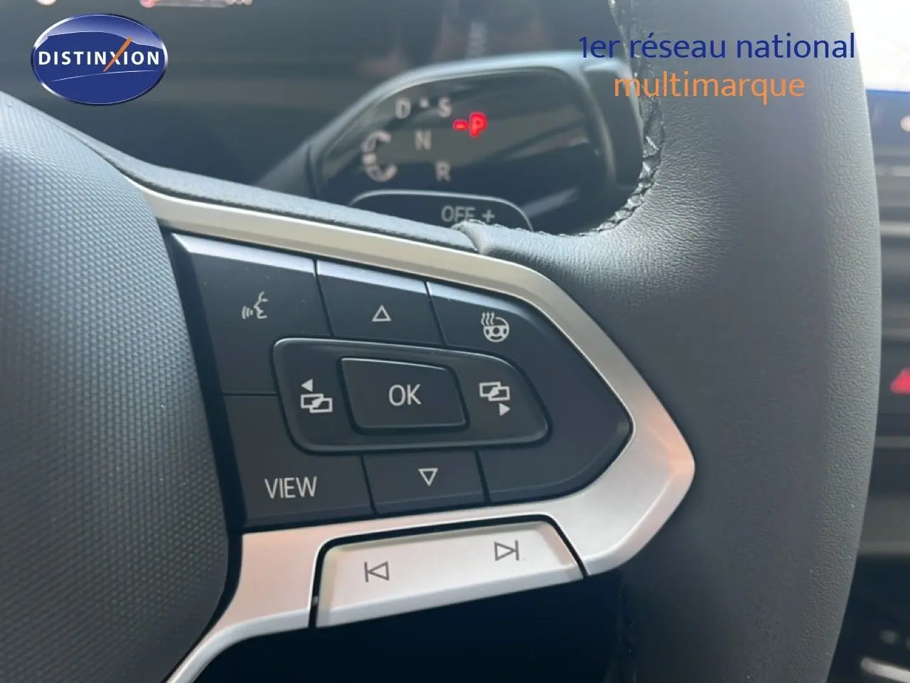 Gros plan sur les commandes gauche du volant noir du Volkswagen Tiguan 2026, soulignant les boutons multifonctions et finition argentée.