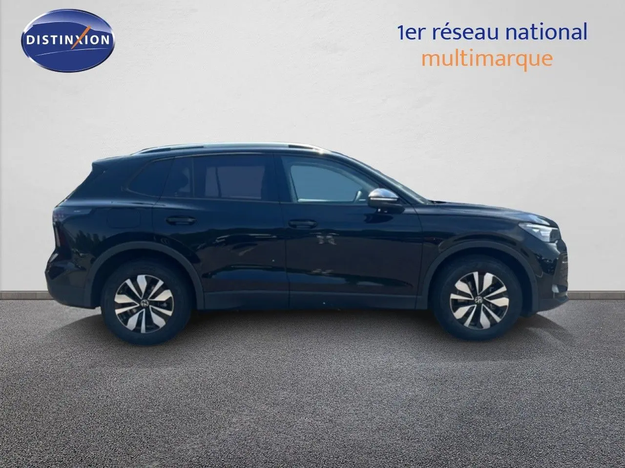 Vue de profil côté gauche d'un Volkswagen Tiguan noir métallisé, avec jantes distinctives et lignes épurées.